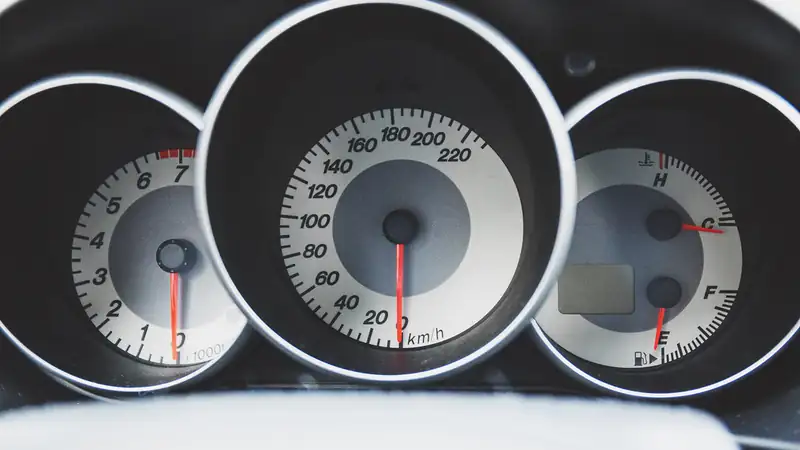 A car instrument cluster with a speedometer, a tachometer and temperature and fuel gauges.