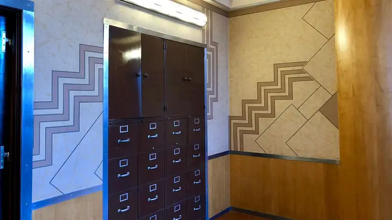 A wall of dark wooden file drawers in an art deco office.