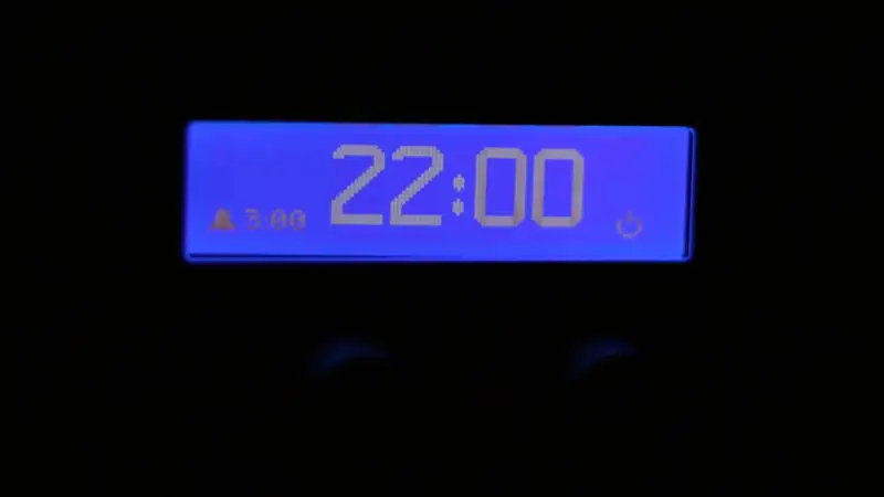 A digital clock display glowing blue in a dark room.
