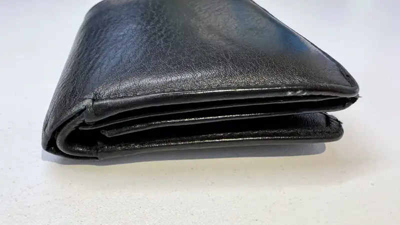 A worn black leather wallet folded on a light table.